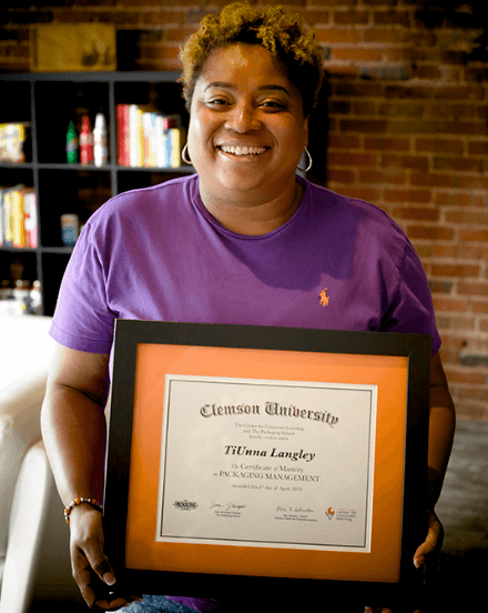 Certificate of Mastery graduate holding their framed Clemson certificate